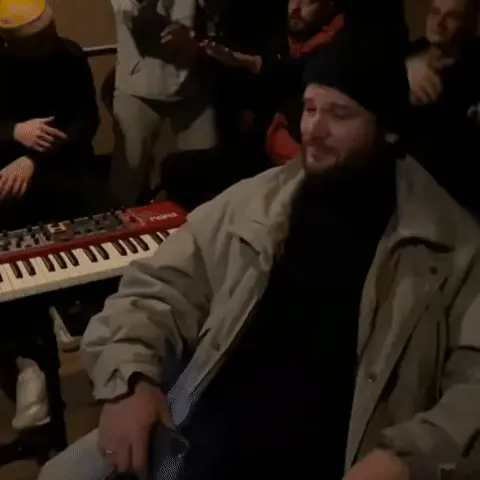 Мужчина ритмично кивает головой в такт, сохраняя спокойное и слегка скептичное выражение лица. — мужчина в черной шапке