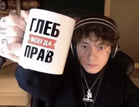 Человек подносит кружку к камере, демонстрируя надпись, и удерживает её в кадре. — Три дня дождя (Глеб Викторов)