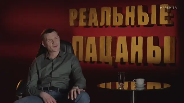 Мужчина сидит в кресле, слегка покачивается, произносит реплику с ухмылкой. — Николай Наумов