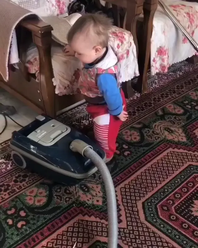 Маленький помощник пылесосит