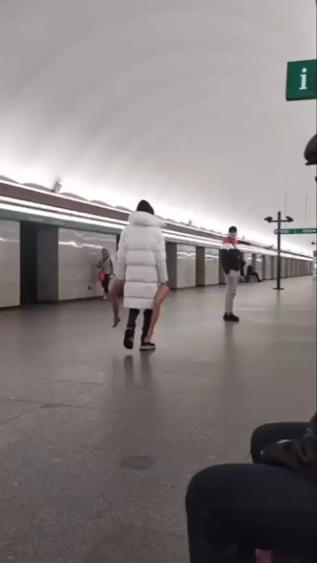 Парень несёт девушку под курткой в метро