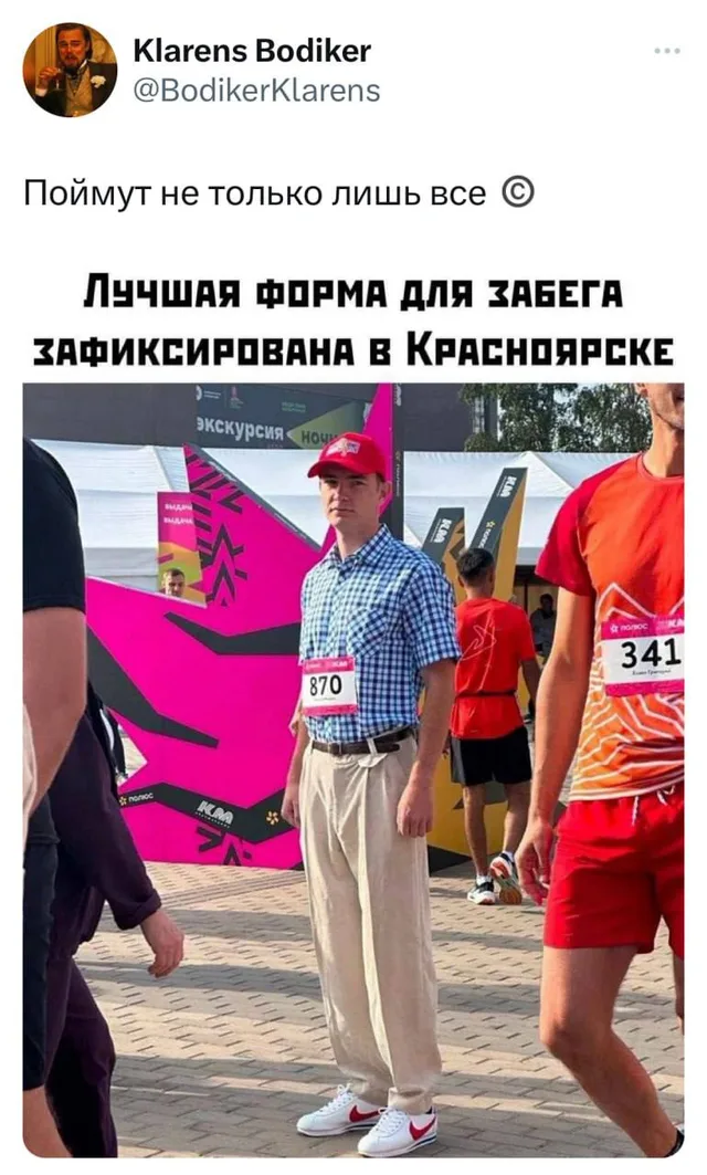 Парень стоит в толпе участников забега, выделяясь своим подчеркнуто повседневным, «офисным» или «дачным» стилем одежды на фоне людей в спорт