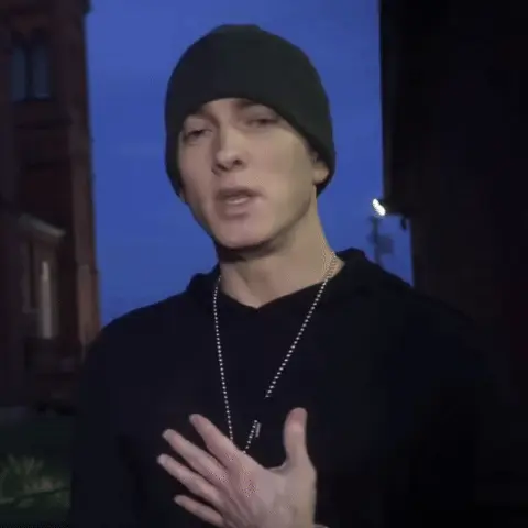 Эминем смотрит в камеру, что-то говорит и делает характерный жест рукой, как будто пытается объяснить очевидную вещь или выражает недоумение
