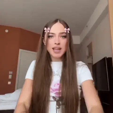 Девушка активно трясет головой и телом в такт невидимой музыке, совершая резкие движения руками перед собой. — девушка с бантиками в волосах