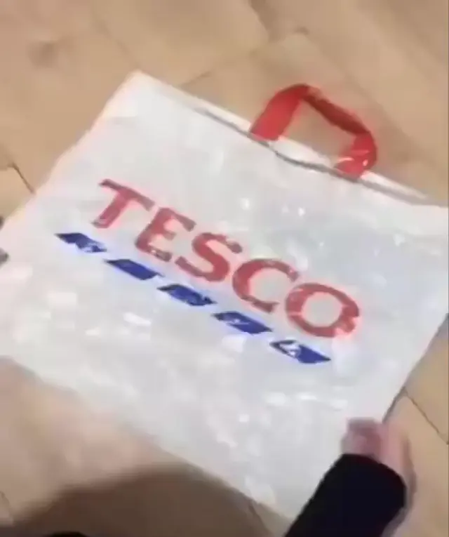 Руки поэтапно складывают пакет Tesco вдоль и по диагонали в треугольник, фиксируют ручку и открывают выдвижной ящик, где ровными рядами улож