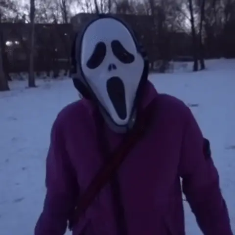 Человек в маске стоит на месте и ритмично покачивает головой из стороны в сторону в такт музыке (которая подразумевается, но не слышна). — ч