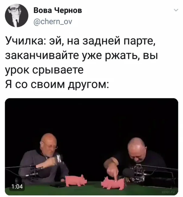 Два мужчины сидят за столом с микрофонами и розовыми свинками, один пытается сдержать смех, закрывая рот рукой, другой тычет пальцем в игруш