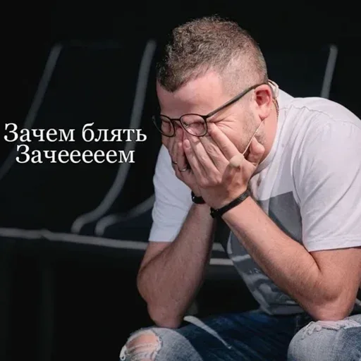 Мужчина сидит в позе «испанского стыда» или глубокого отчаяния, обхватив голову руками. — мужчина в очках и белой футболке