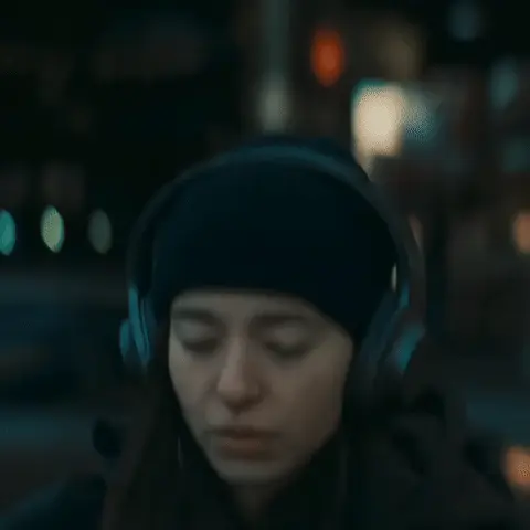 Девушка подносит руку ко рту, делает затяжку, затем медленно опускает руку, продолжая смотреть в одну точку. — девушка в черной шапке и науш