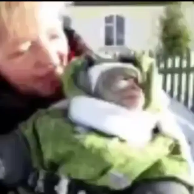 Обезьянка в комбинезоне гуляет по снегу