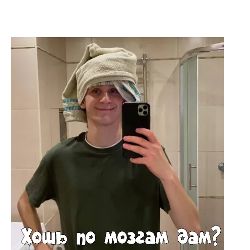 Парень держит телефон перед собой, фотографируя свое отражение в зеркале. — молодой человек в полотенце на голове