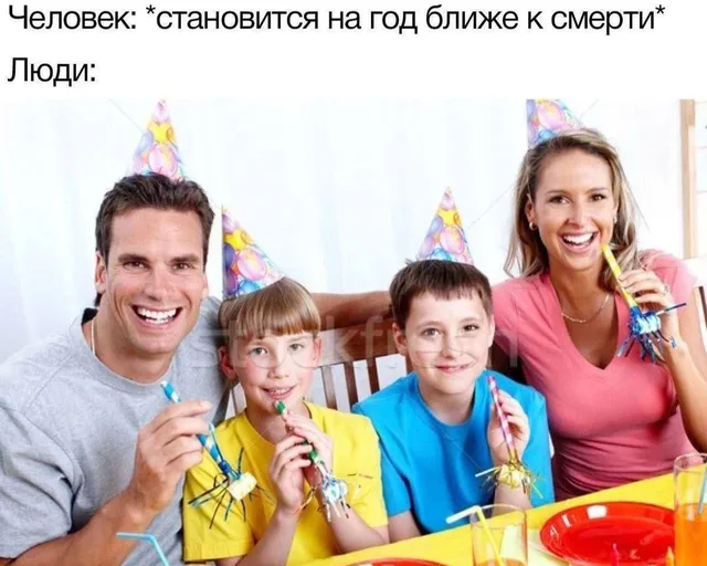 Семья радостно сидит за столом, держа в руках праздничные дудки и позируя для фото