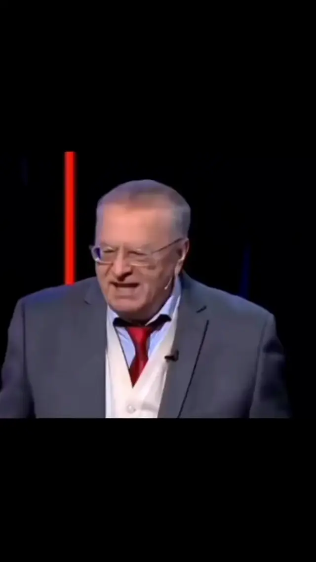 Жириновский говорит перед трибуной, затем камера переключается на Соловьёва в черном френче, который молча слушает с ухмылкой. — Владимир Жи