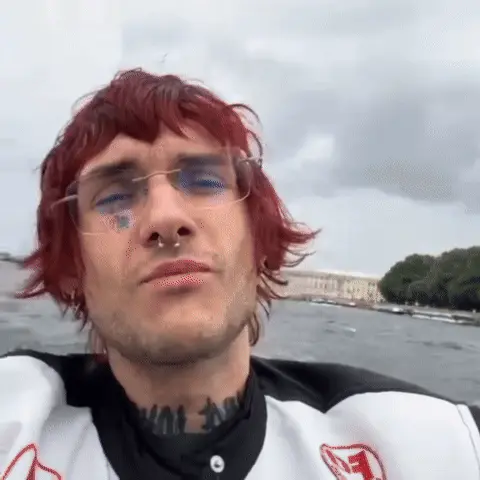 Человек снимает себя на камеру, пока катер движется по воде, волосы развеваются на ветру. — LOVV66, молодой человек с красными волосами