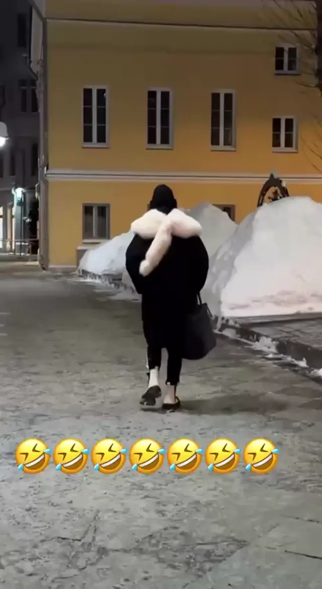 Человек идет спиной к камере, меховой аксессуар на плечах покачивается при ходьбе. — человек в черном пальто