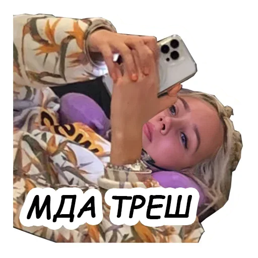 Девушка лежит с телефоном в руках, фиксируя момент для стикера. — девушка со светлыми волосами