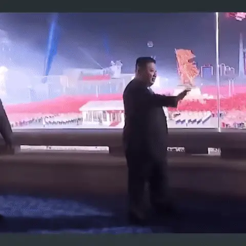 Мужчина идет вдоль балкона, периодически помахивая рукой в приветствии, движение зациклено. — Ким Чен Ын