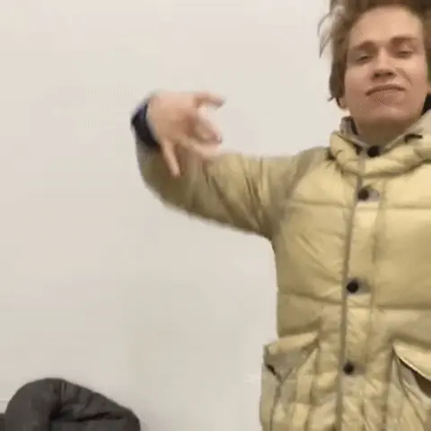 Парень на переднем плане ритмично двигает руками в жестах «рэперского флекса», покачиваясь из стороны в сторону, в то время как человек на п
