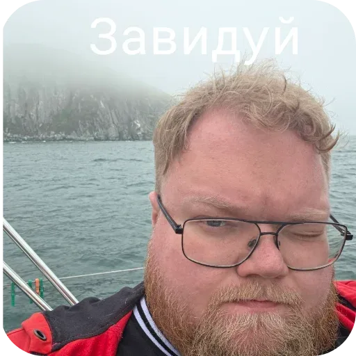 Мужчина держит камеру перед собой, делая селфи на фоне воды. — Антон Татыржа (T2x2), мужчина с рыжей бородой в очках