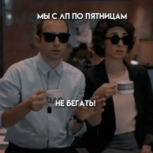 Мужчина и женщина сидят неподвижно, мужчина делает предостерегающий жест рукой. — мужчина в очках и светлой рубашке, женщина в очках и черно