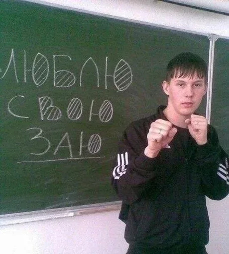 Парень стоит в боевой стойке боксера, подняв кулаки к лицу, демонстрируя готовность к драке — молодой человек в спортивном костюме
