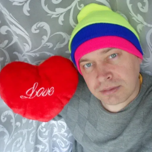 Мужчина держит подушку-сердце перед собой, глядя в объектив. — Геннадий Горин