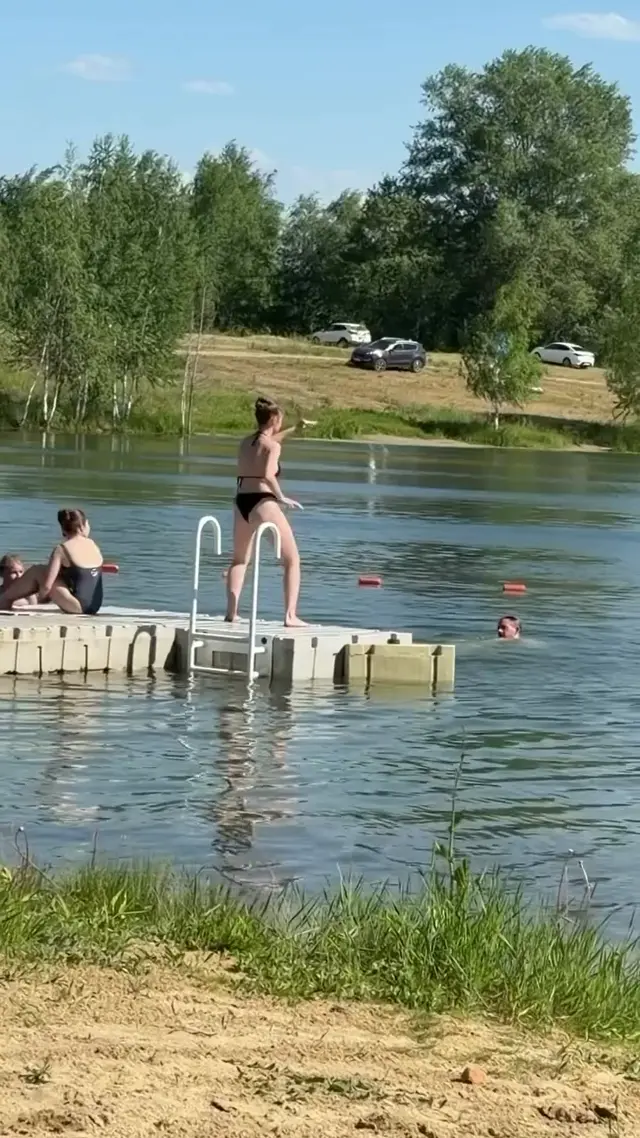 Девушка на понтоне делает махи руками, затем совершает прыжок в воду. — девушка в купальнике