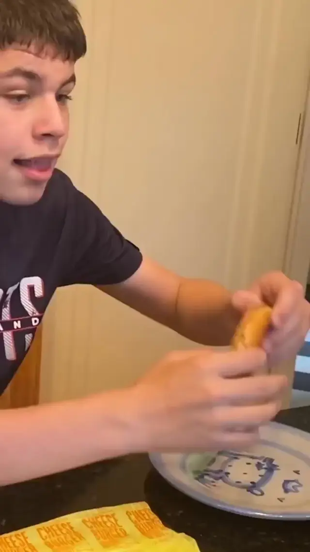 Парень с огромным ртом ест бургеры и засовывает кулак в рот