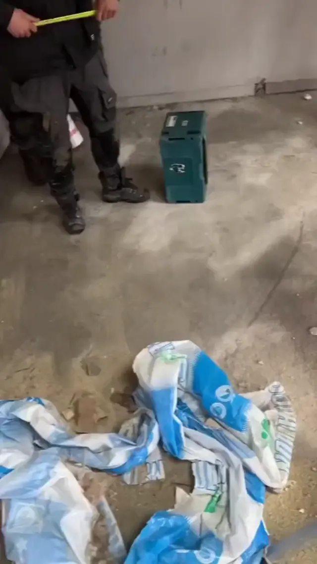 Один рабочий делает из складного метра подобие арбалета и целится по сторонам, а второй встает за ним и складывает руки над головой, изображ