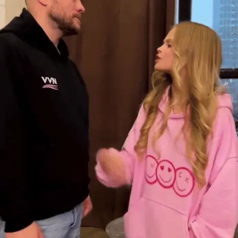Милана Стар активно жестикулирует правой рукой, продолжая говорить, мужчина стоит без движения. — Милана Стар, мужчина в черной худи